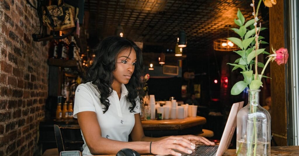 Young woman in a casual cafe working on her laptop, surrounded by rustic decor and flowers.