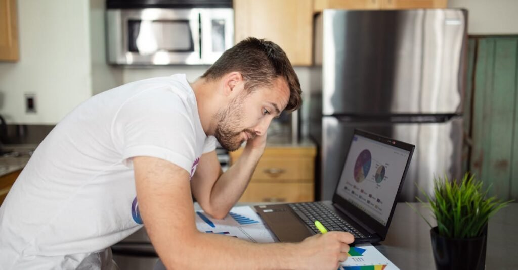 A man reviewing financial charts on a laptop at home, emphasizing data analysis.